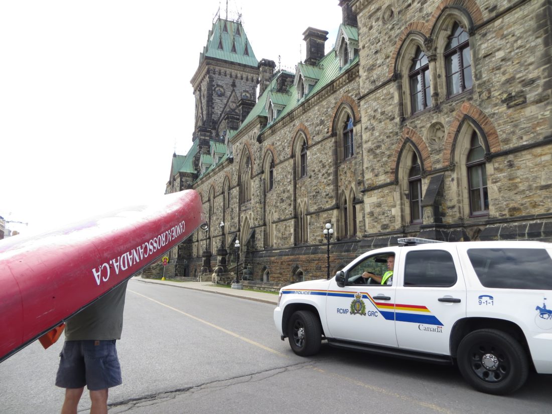 Police car pulls up as Geoff portages the canoe towards the Parliament buildings for a triumphant photo.